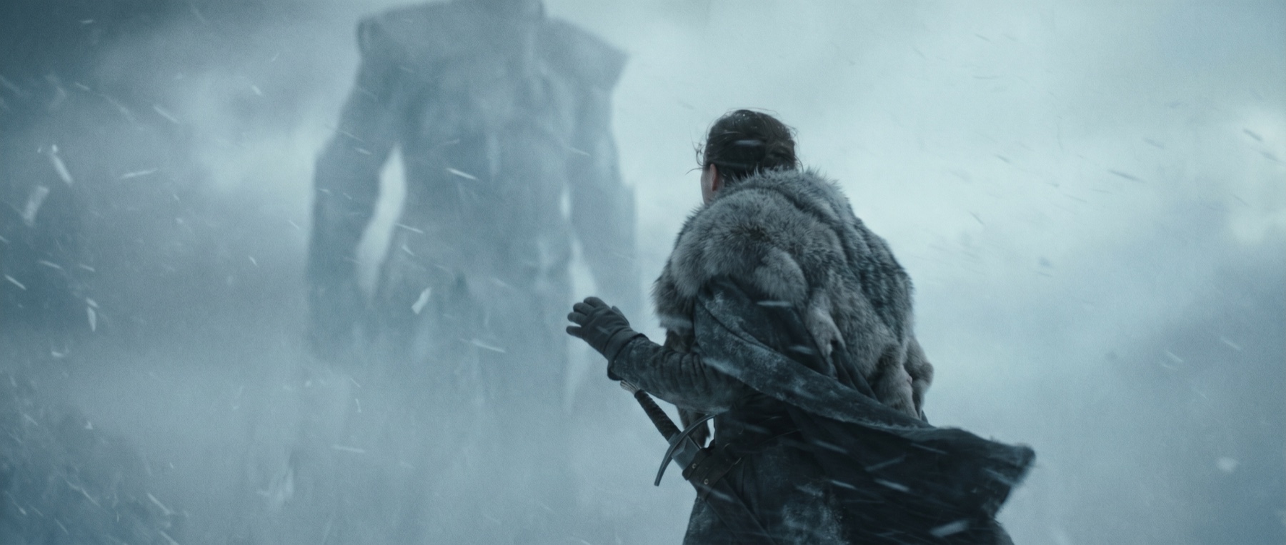 An explorer facing an ancient colossus in a snowstorm.